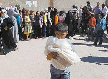 Menino carrega pes distribudos no fim do Ramad em Azaz; conflito no pas prejudica o abastecimento da populao
