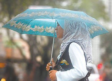 Mulher se protege de chuva ontem, no centro de So Paulo, que teve queda de temperatura
