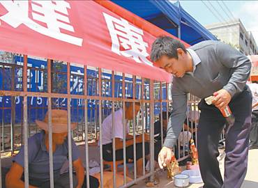 Turista na cidade chinesa de Xinjian, no leste do pas, deposita moeda para mendigo detido em jaula na rua por determinao da prefeitura local