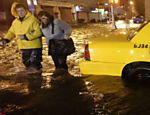 Pedestres passam ao lado de táxi submerso, no Brooklyn Leia mais