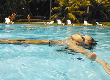 Garota em piscina do clube Magic Gardens, em Ribeiro