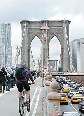Ciclista e pedestres atravessam ponte do Brooklyn, em NY
