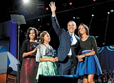 Abraado  filha Malia e ao lado da caula, Sasha, e da mulher, Michelle, Barack Obama acena, aps o discurso da vitria, em Chicago