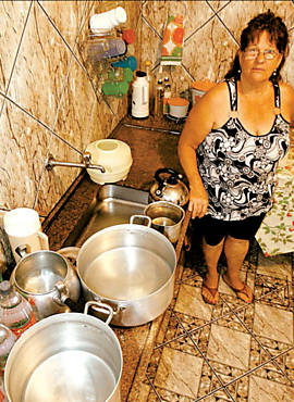 Maria Aparecida Faria mostra vasilhas onde guarda gua