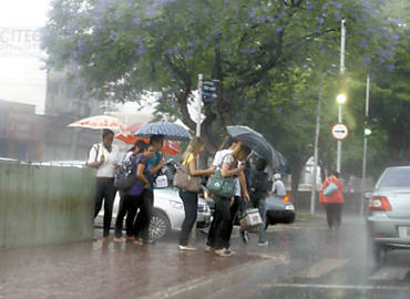 Sob temporal, pedestres tentam atravessar a avenida Francisco Junqueira, em Ribeiro; chuva deve continuar hoje