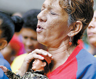 Apoiadora de Chvez segura boneco do presidente em missa por sua sade em Caracas