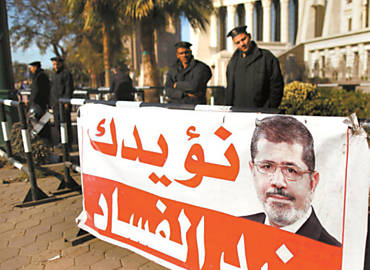 Policiais atrs de cartaz do presidente Mursi, posto diante da corte constitucional egpcia