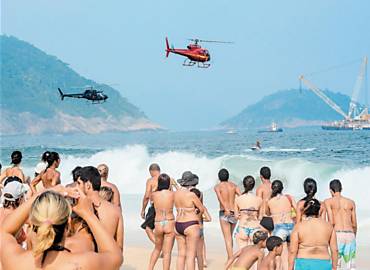 Banhistas observam manobras de resgate dos quatro bombeiros que estavam a bordo de helicptero que caiu no Rio