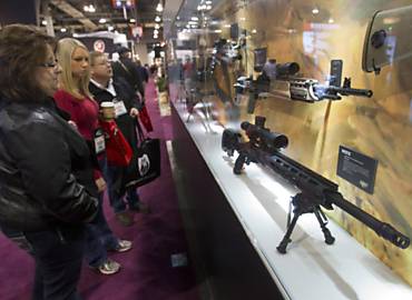 Participantes de uma feira anual de armas em Las Vegas, no Estado de Nevada, observam diferentes fuzis em vitrine