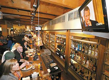 Frequentadores de bar em Utah, nos EUA, acompanham a entrevista de Armstrong na TV