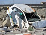 Policial observa veículo destruído em Namie, perto de Fukushima, no Japão