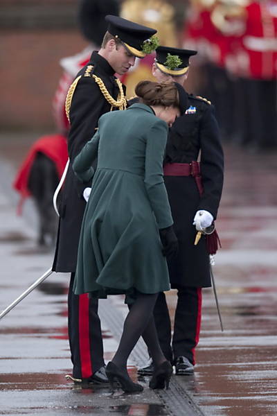 Príncipe William (à esq.) ajuda Kate Middleton a tirar o salto dela, que enganchou em um buraco, em uma visita a Aldershot, no sul da Inglaterra, no Dia de São Patrício