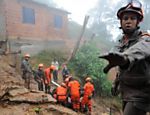 Bombeiros e agentes da Defesa Civil trabalham para retirar o corpo de uma das vítimas de um deslizamento de terra em Petrópolis