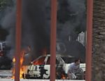 Moradores se escondem perto de carro em chamas durante confrontos entre grupo islâmico e unidade do Exército líbio, na Líbia