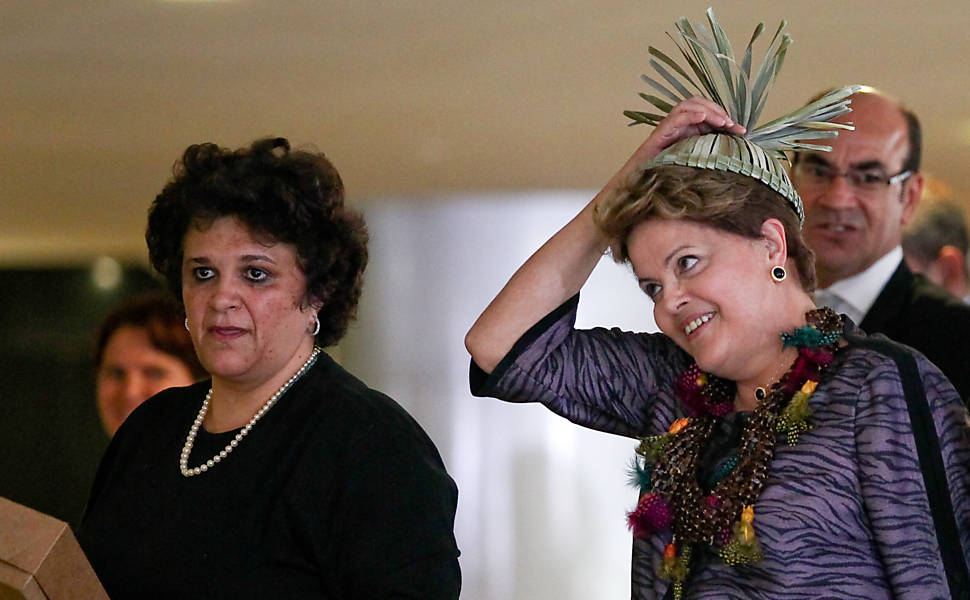 Dilma, ao lado da ministra do Meio Ambiente Izabella Teixeira, coloca adereço indígena chamado barritina, da tribo pernambucana Xucuru, após cerimônia de recepção dos participantes da IV Conferência Nacional Infantojuvenil pelo Meio Ambiente, no Palácio do Planalto