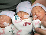 Os pais Hannah e Tom Hepner seguram os trigêmeos idênticos Abby, Laurel e Brindabella em uma sala de auto-atendimento em Sacramento, Califórnia, nos Estados Unidos; os trigêmeos idênticos, caso raro na medicina, nasceram no Hospital Sutter Memorial em 22 de novembro