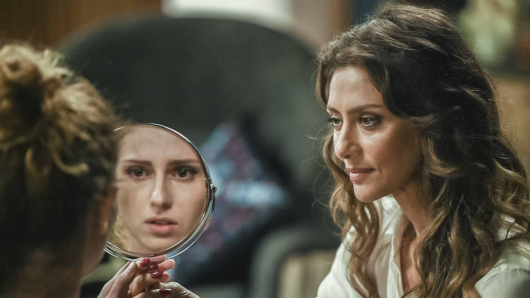 Joyce  (Maria Fernanda Candido) maquiou Ivana (Carol Duarte) e segura o espelho para que ela veja