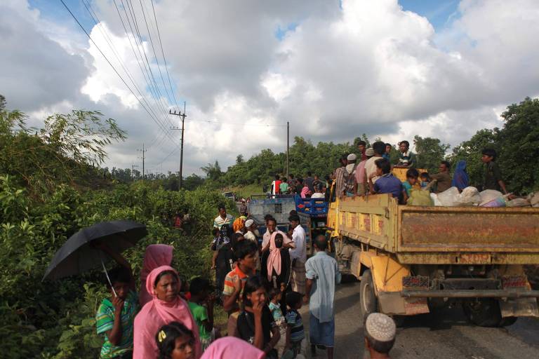 Muulmanos da minoria rohingya colocam seus pertences em caminhes ao chegarem a Bangladesh