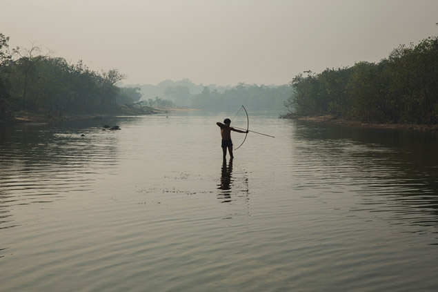 Indgena pesca com arco e flecha em um rio no Parque Indigena do Xingu, Mato Gosso