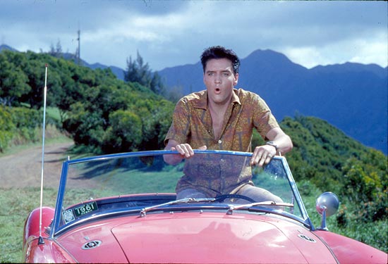 Elvis Presley em cena de "Feitiço Havaiano", de 1961; o carro vermelho usado no filme está na exposição