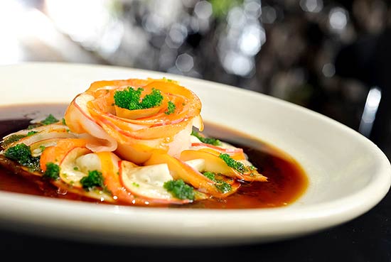 Prato do JAM, o Ussuzuki Haddock são finas fatias de hadoque defumado envoltos com sashimi de caju e tobiko wasabi 
