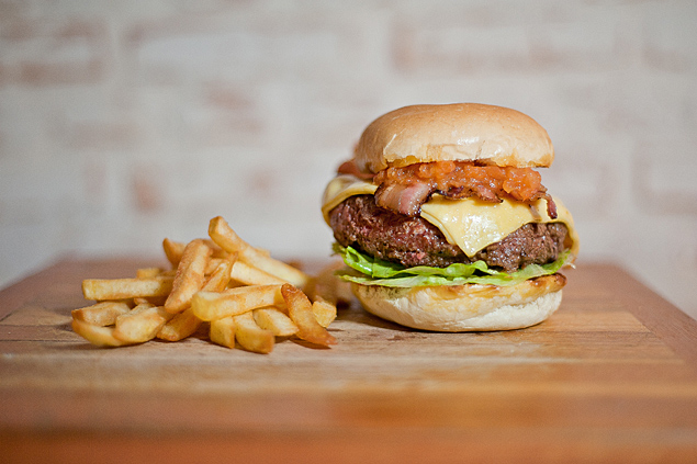 O Holy Burger leva queijo prato, alface, cebola roxa, picles, maionese, molho de tomate e bacon