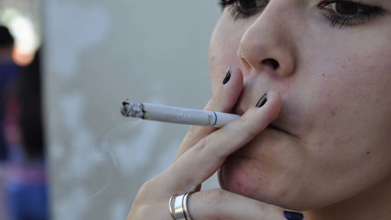 Mulher fumando cigarro convencional