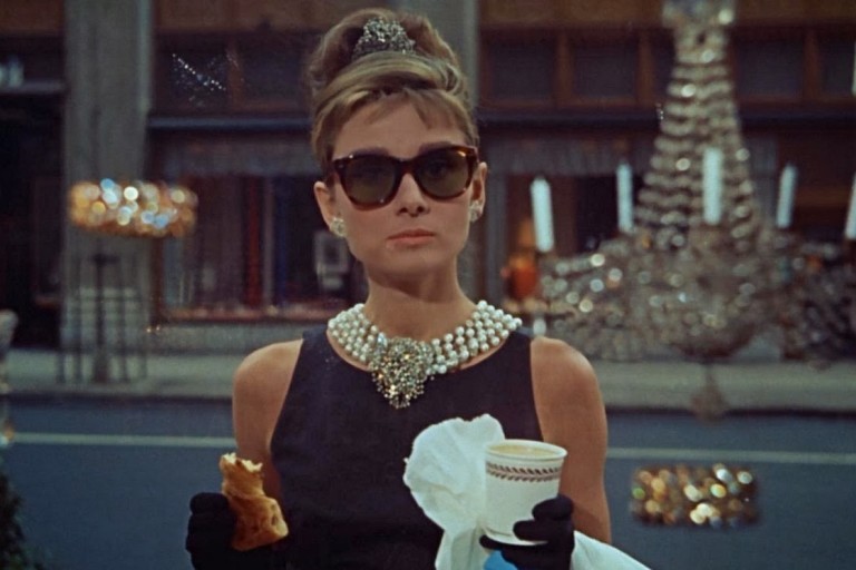 Audrey Hepburn com seu café e um croissant no filme "Bonequinha de Luxo"