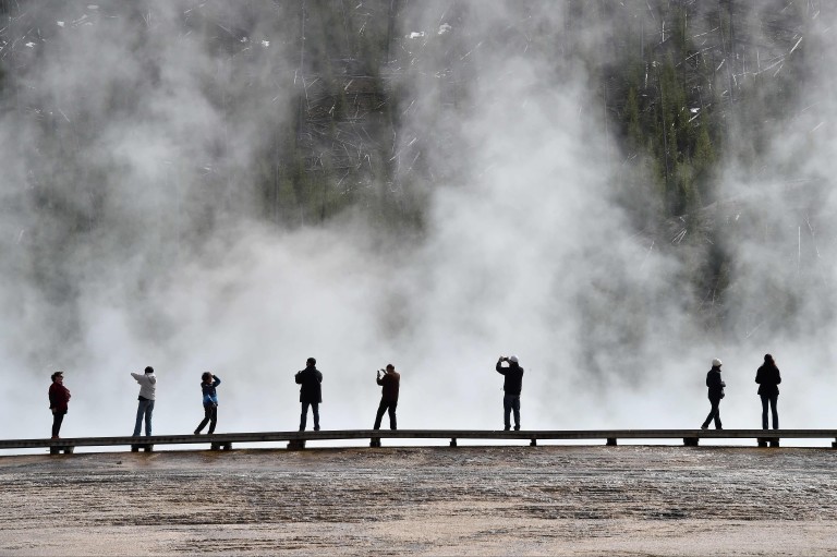 (FILES) This file photo taken on May 11, 2016 shows  Tourists at the Grand Prismatic Springin Yellowstone National Park. Colin Nathaniel Scott, 23, of Oregon, accidentally fell into a hot spring on Ju