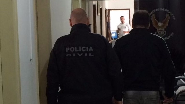 O ex-Polegar Ricardo Costa (dir.) é conduzido pela polícia