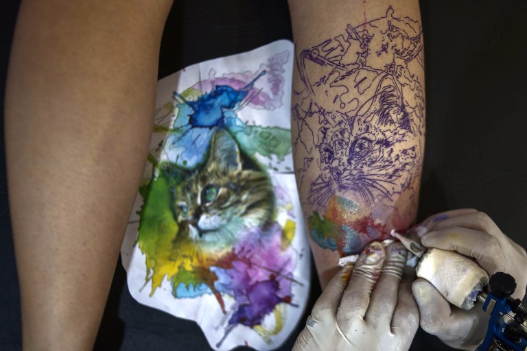 A tattoo artist makes a tattoo on the leg of a woman during the Tattoo Week in Sao Paulo, Brazil, July 14, 2017. / AFP PHOTO / Miguel SCHINCARIOL