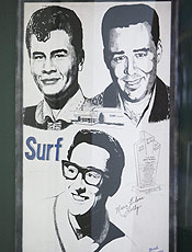 Pôster dos pioneiros do rock Buddy Holly (de óculos), Ritchie Valens (à esquerda) e J.P. "The Big Bopper" Richardson pendurado no Surf Ballrom, em Iowa, onde eles fizeram o último show antes do acidente fatal.