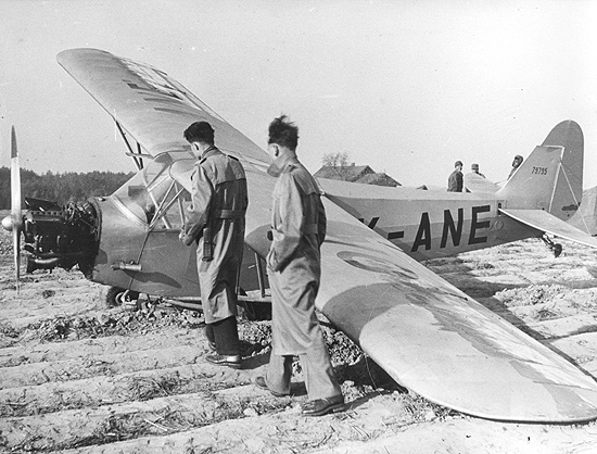 Foto de 1953 de Jiri Wertheimer e Zdenek Volf (à dir.) olhando o avião recém-pousado no qual fugiram