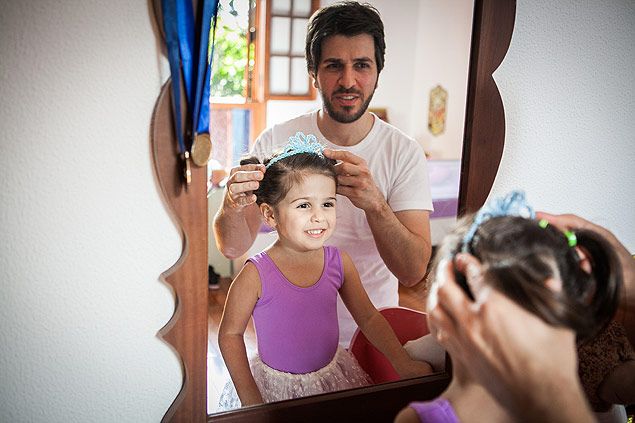 O designer paulistano Juca Orlandi prepara a filha Alice, 4, para a aula de bal 