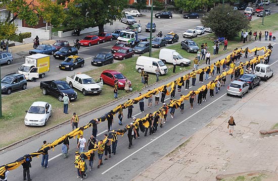 ORG XMIT: PP006 Uruguayan Penarol?s team fans carry what is supposed to be the largest football supporters' flag (309 X 46 m) outside Centenario stadium in Montevideo on April 12, 2011. The fans made the flag, which costed about 30,000 dollars and will be displayed on Tuesday for the first time during the Libertadores Cup match against Argentinian team Independiente. AFP PHOTO/Pablo PORCIUNCULA