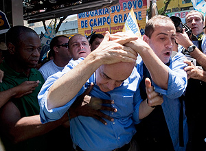 José Serra protege a cabeça após levar pancada durante confusão com militantes do PT em caminhada na zona oeste do Rio