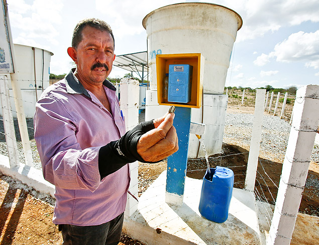 Secretário de Agricultura de Riacho das Almas, Naelson Beserra, segura ficha usada no 'orelhão' da água, parte de sistema que extrai e dessalinizar água do solo