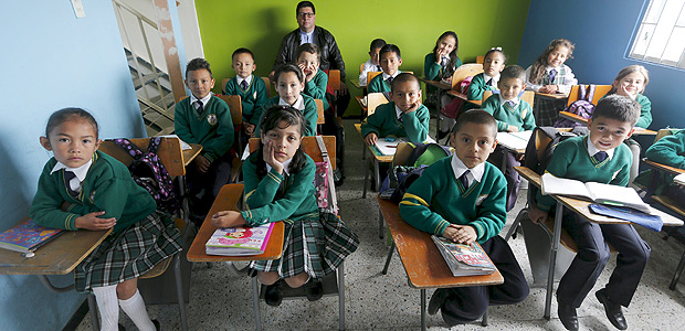 Teacher Father Juan Humberto Cruz poses for pictures with 4th grade students at Semillas de Esperanza (Seeds of Hope) school in Soacha, near Bogota, Colombia, June 11, 2015. Nearly three years after Taliban gunmen shot Pakistani schoolgirl Malala Yousafzai, the teenage activist last week urged world leaders gathered in New York to help millions more children go to school. World Teachers' Day falls on 5 October, a Unesco initiative highlighting the work of educators struggling to teach children amid intimidation in Pakistan, conflict in Syria or poverty in Vietnam. Even so, there have been some improvements: the number of children not attending primary school has plummeted to an estimated 57 million worldwide in 2015, the U.N. says, down from 100 million 15 years ago. Reuters photographers have documented learning around the world, from well-resourced schools to pupils crammed into corridors in the Philippines, on boats in Brazil or in crowded classrooms in Burundi. REUTERS/John Vizcaino PICTURE 9 OF 47 FOR WIDER IMAGE STORY "SCHOOLS AROUND THE WORLD"SEARCH "EDUCATORS SCHOOLS" FOR ALL IMAGES ORG XMIT: PXP09