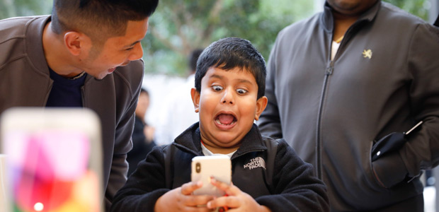A boy makes faces while testing out the Animoji feature on an iPhone X at the Apple Store Union Square on November 3, 2017, in San Francisco, California. Apple's flagship iPhone X hits stores around the world as the company predicts bumper sales despite the handset's eye-watering price tag, and celebrates a surge in profits. / AFP PHOTO / Elijah Nouvelage