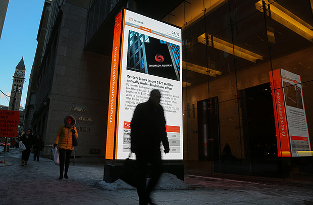 A man passes a digital billboard showing news of talks between Thomson Reuters and U.S. private equity firm Blackstone Group LP, outside the Thomson Reuters offices in Toronto, Ontario, Canada January 30, 2018. REUTERS/Chris Helgren ORG XMIT: TOR500