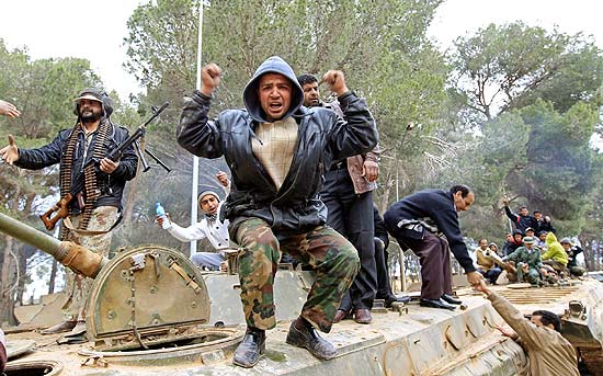 Rebeldes da oposição celebram a tomada da cidade de Shabat, na região leste, sobre um tanque de guerra do Exército da Líbia