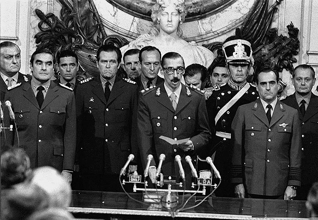 Ladeado por Emilio Massera (esq.) e Orlando Agosti, o general Videla  empossado presidente, cinco dias aps o golpe