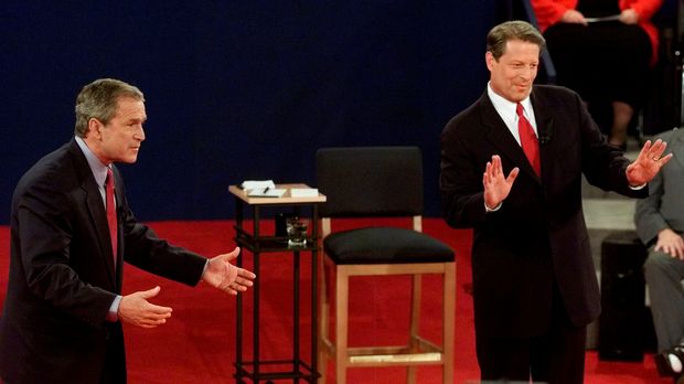  Republican presidential candidate and Texas Governor George W. Bush (L) and Democratic presidential candidate U.S. Vice President Al Gore both gesture toward moderator Jim Lehrer during the town hall-style presidential debate at Washington University in St. Louis, U.S., October 17, 2000. REUTERS/Jeff Mitchell/File Photo ORG XMIT: WAS457