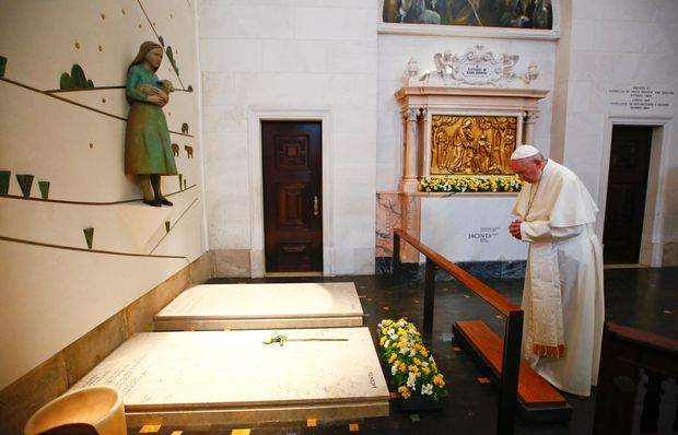 Pope Francis prays in front of the grave of two of the three little sheperds at the Shrine of Our Lady of Fatima in Portugal on May 13, 2017. The two young shepherds, Jacinta and Francisco Marto, who had visions of the Virgin Mary 100 years ago in Fatima, a Portuguese site now a global draw for pilgrims, were declared saints today by Pope Francis. / AFP PHOTO / POOL / TONY GENTILE