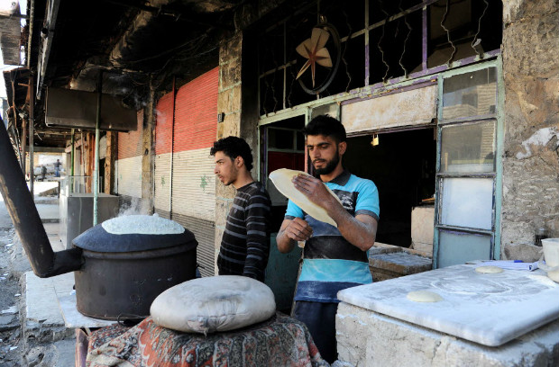 Homens assam pão em Madaya, cidade que sofreu com a fome devido ao cerco do regime sírio