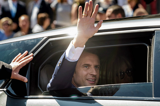 French President Emmanuel Macron (L) waves next to his wife Brigitte Macron as they leave after voting at a polling station during the first round of the French legislative election in Le Touquet, on June 11, 2017. French voters went back to the polls on June 11 for the first round of parliamentary elections that are predicted to give President Emmanuel Macron's centrist party a commanding majority. / AFP PHOTO / POOL / Christope Petit Tesson