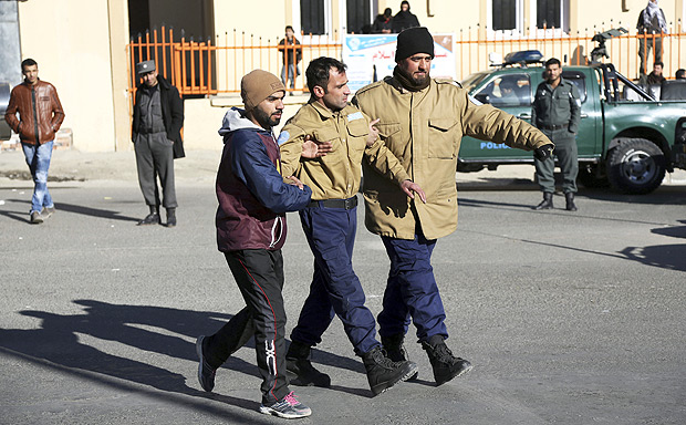 Afghan security personnel escort a man rescued from the Intercontinental Hotel after an attack in Kabul, Afghanistan, Sunday, Jan. 21, 2018. Gunmen stormed the hotel and sett off a 12-hour gun battle with security forces that continued into Sunday morning, as frantic guests tried to escape from fourth and fifth-floor windows. (AP Photo/Rahmat Gul) ORG XMIT: XRG106