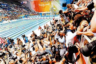 Michael Phelps, cercado por fotgrafos, tenta beijar sua me e sua irm aps vencer competio 4x100 m
