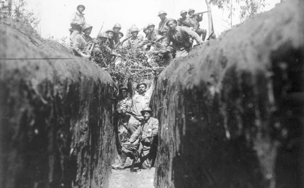 Imagem dos soldados cobrindo a trincheira com vegetação para camuflá-la, durante a Revolução de 1932