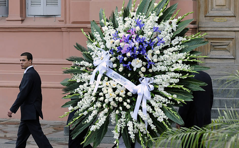 Funcionários carregam coroa de flores enviada pela presidente Cristina Kirchner, viúva de Néstor Kirchner 